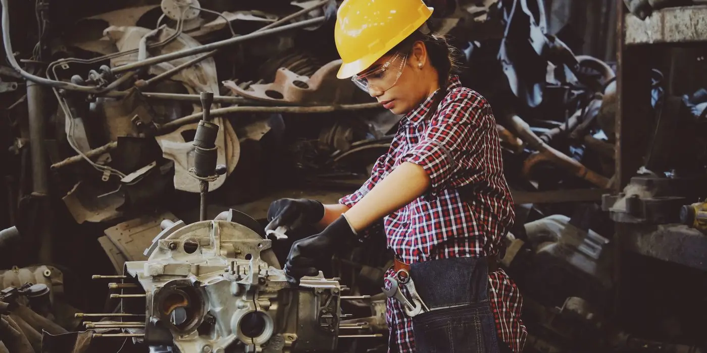 A technician in a hard hat working on industrial machinery